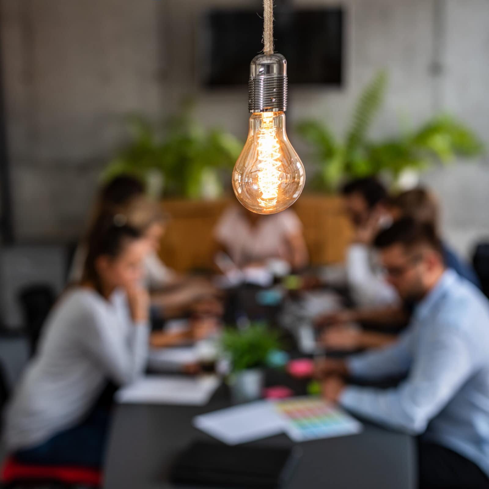 Young creative business people meeting at office. Young business people are discussing together a new startup project. A glowing light bulb as a new idea.