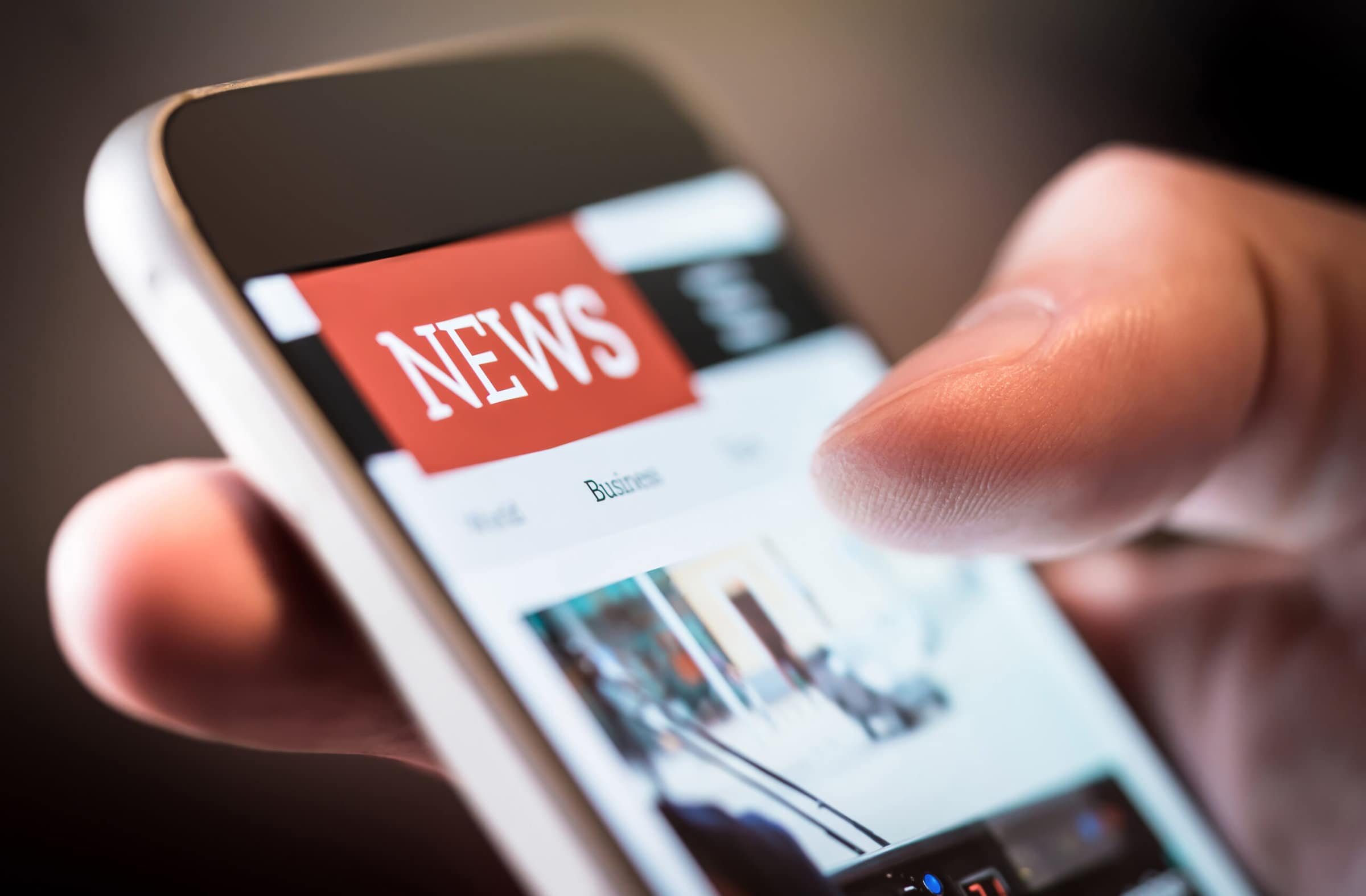 Online news in mobile phone. Close up of smartphone screen. Man Online news in mobile phone. Close up of smartphone screen. Man reading articles in application. Hand holding smart device. Mockup website. Newspaper and portal on internet.