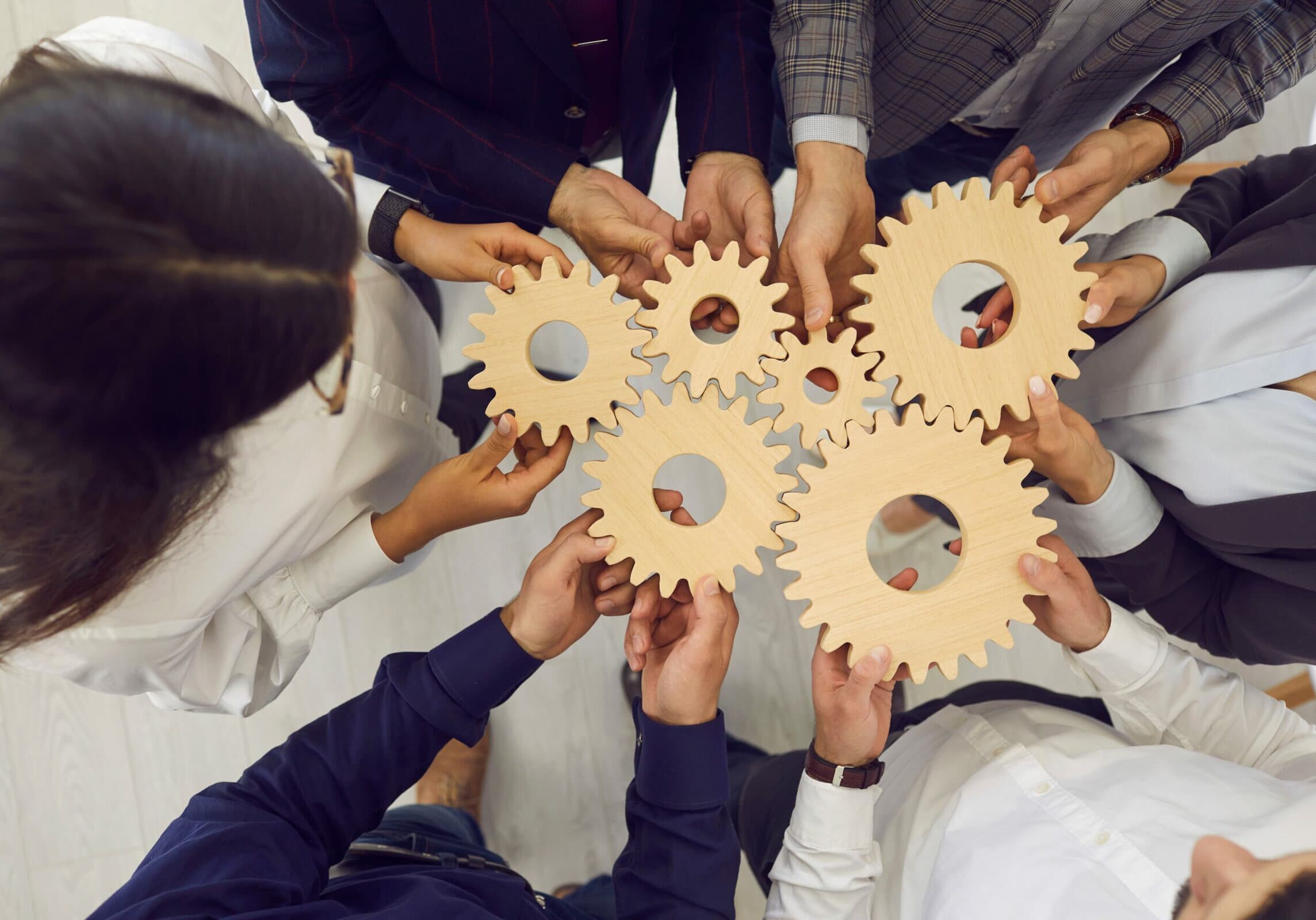 Business team people hands holding gear wheels shot with view from above Business team people hands holding gear wheels shot with view from above