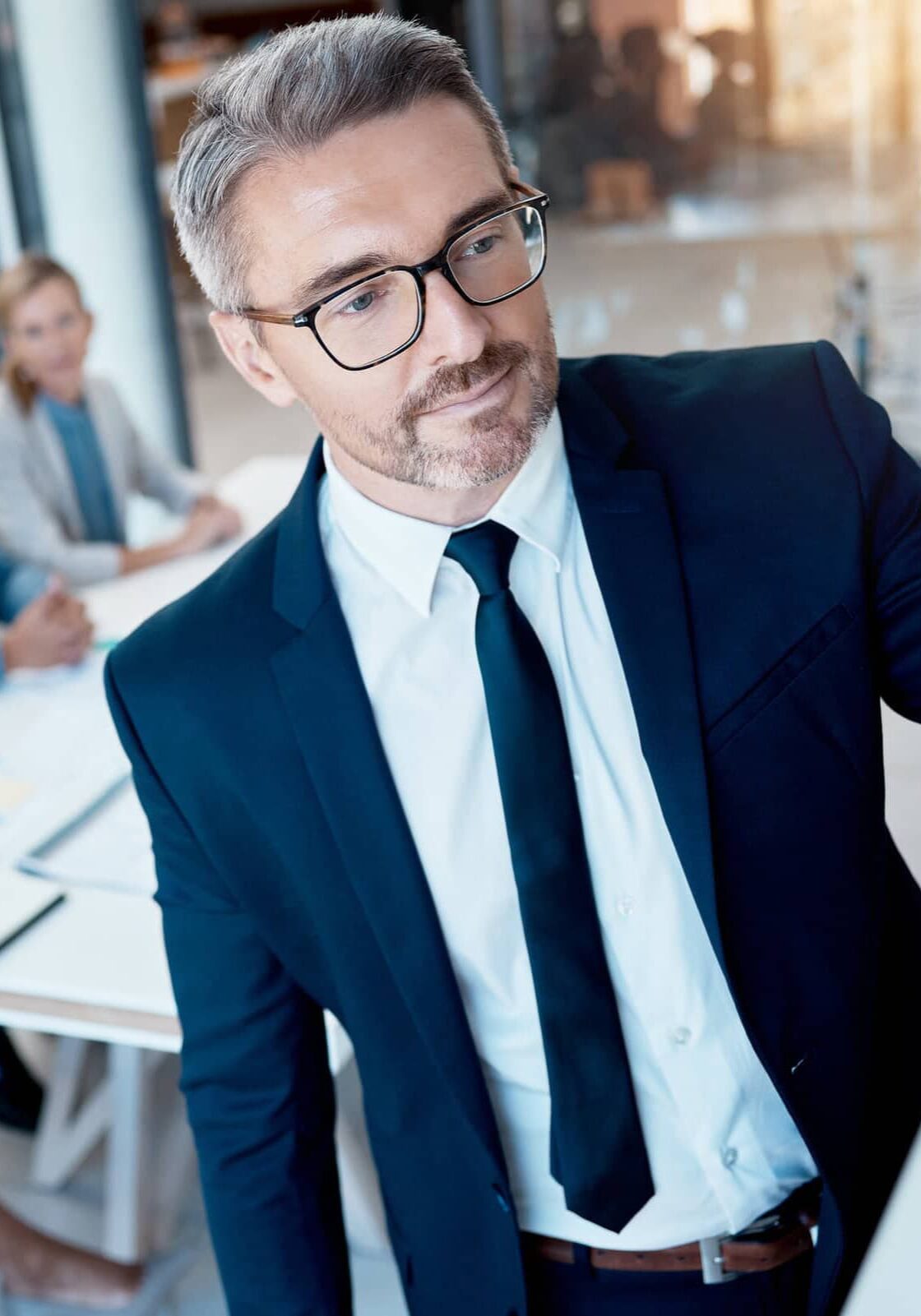 AdobeStock_539141240 mid-age professional writing on board during meeting