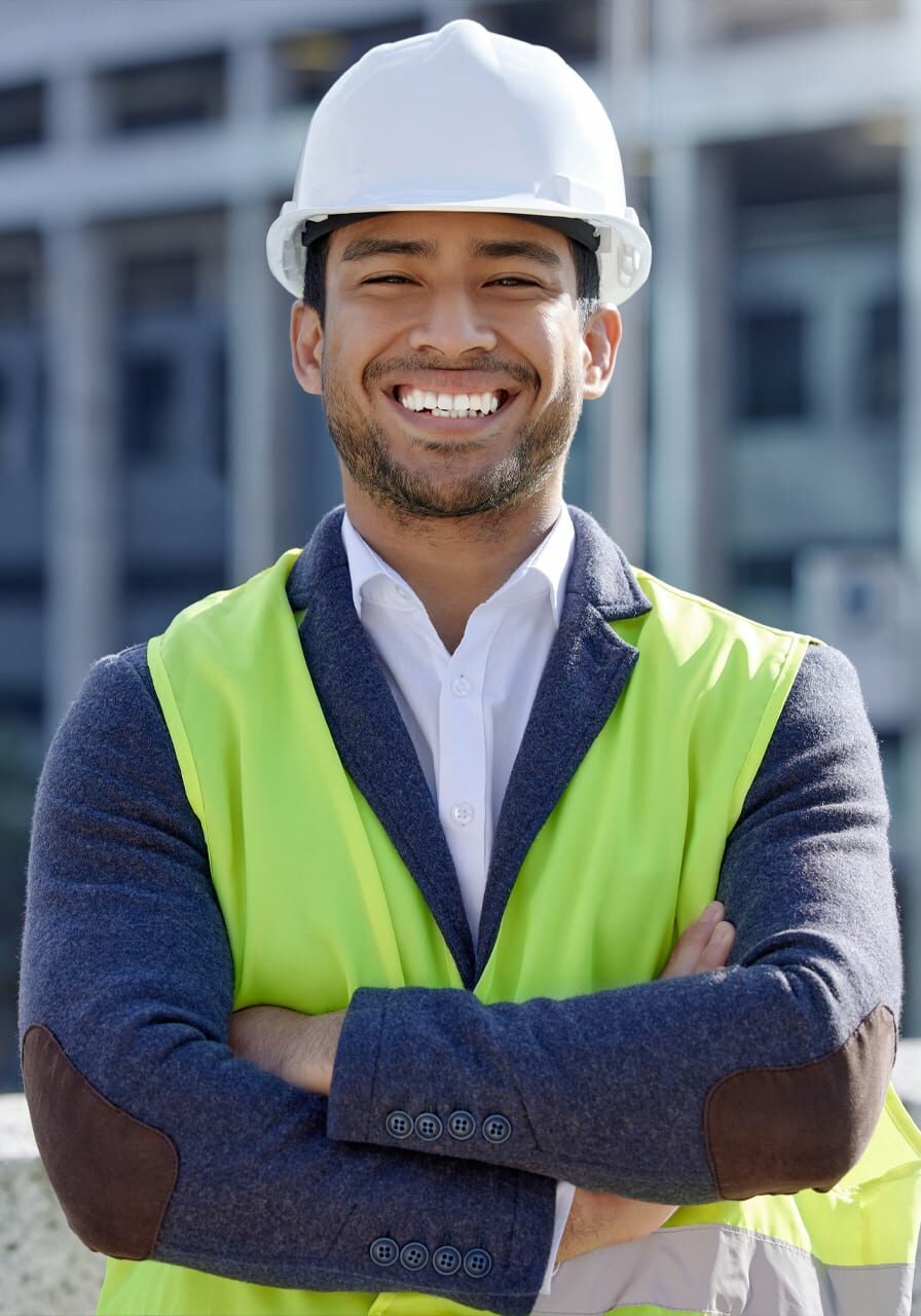Young engineer standing on top of a building with a yellow vest and a hard hat Young engineer standing on top of a building with a yellow vest and a hard hat